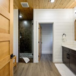 Bathroom with a dark double vanity and a tiled walk-in shower beyond