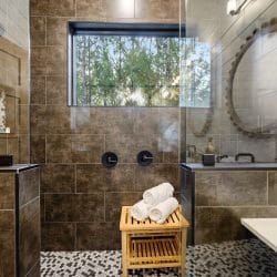 Large tiled shower with a wooden stool, a window and a tub at right