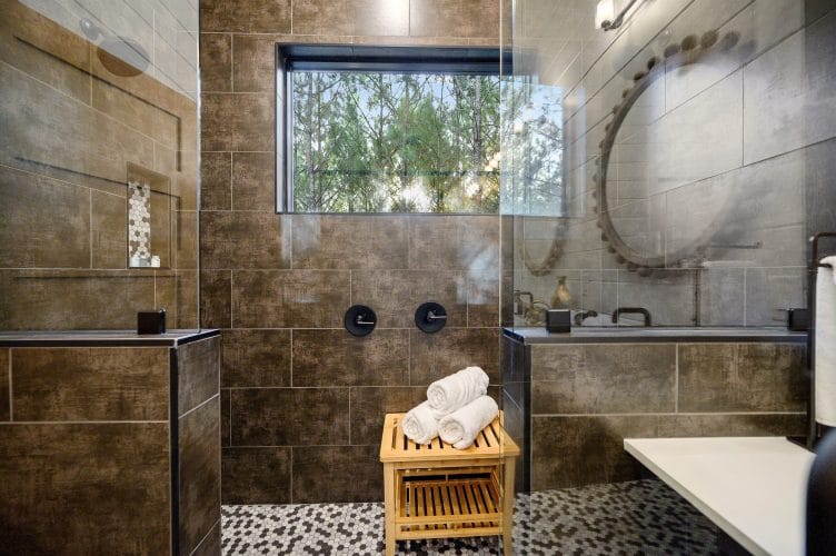 Large tiled shower with a wooden stool, a window and a tub at right
