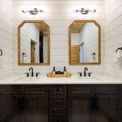 Double vanity with two wood-framed mirrors and black faucets