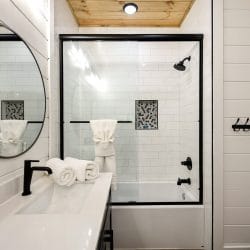 Bathroom with a tub-and-shower, a round mirror and black fixtures