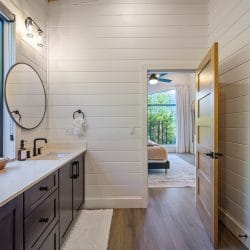 Bathroom with a long dark vanity, a round mirror and a window