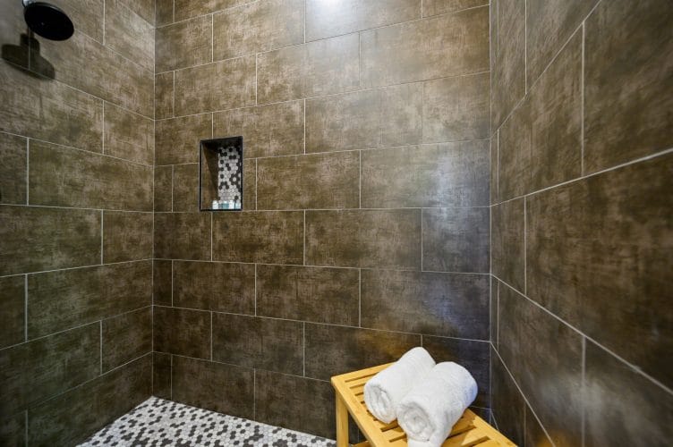 Walk-in shower with large dark tile and a niche