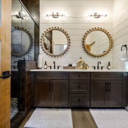 Double vanity with two round beaded-frame mirrors and a glass shower