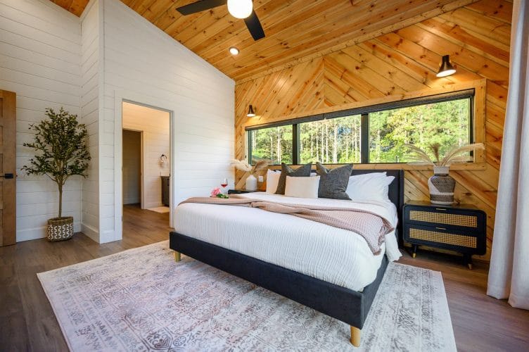 King bed under a herringbone pine accent wall with a long window