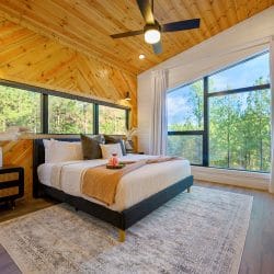 King bed with a mustard throw, a big window and a long dresser
