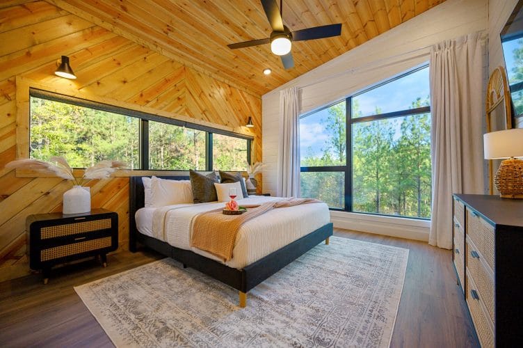 King bed with a mustard throw, a big window and a long dresser