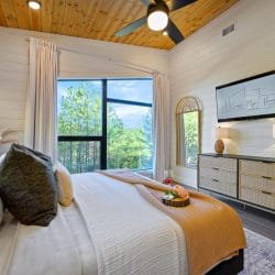 King bed with a TV on the wall, a dresser and a ceiling fan