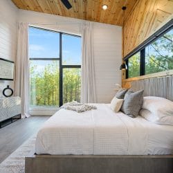 King bed with a gray upholstered frame beside a tall window