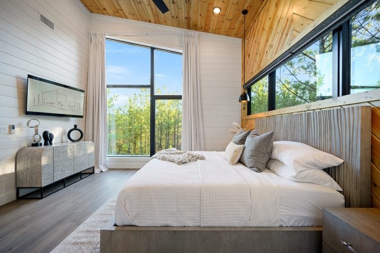 King bed with a gray upholstered frame beside a tall window