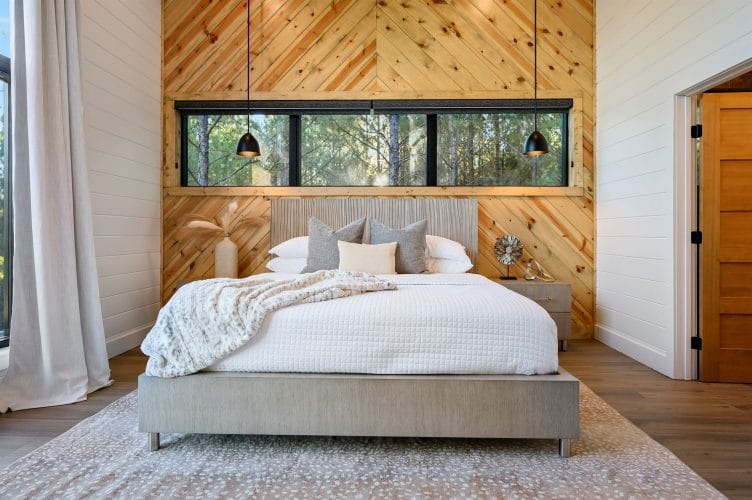 Bed against a herringbone pine accent wall with pendant lights and a long window