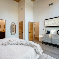 Bed, console and framed art, with a doorway into the bathroom