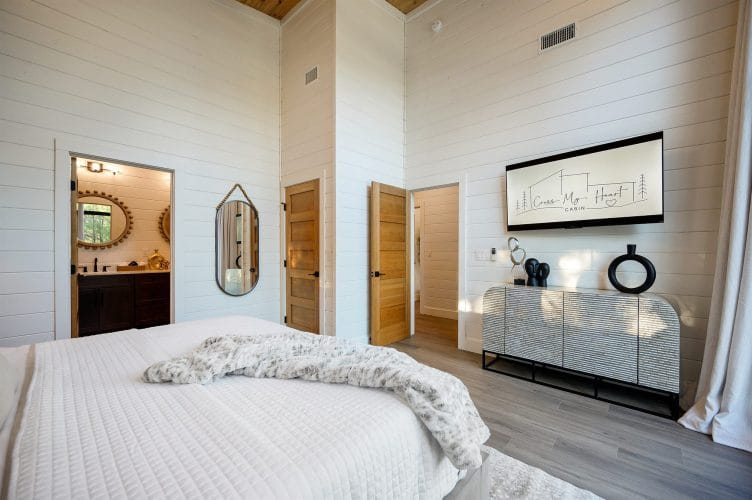 Bed, console and framed art, with a doorway into the bathroom