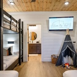 Bunk room with black wood bunks, a wall TV and a gray canvas teepee