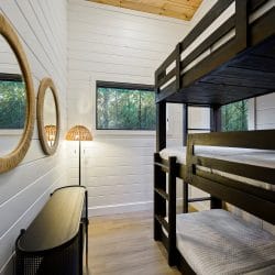 Upstairs bunk room with a black bunk beside round wicker mirrors