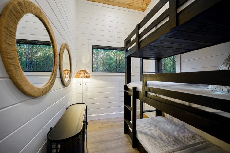 Upstairs bunk room with a black bunk beside round wicker mirrors