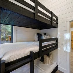 Black bunk with white bedding beside a window