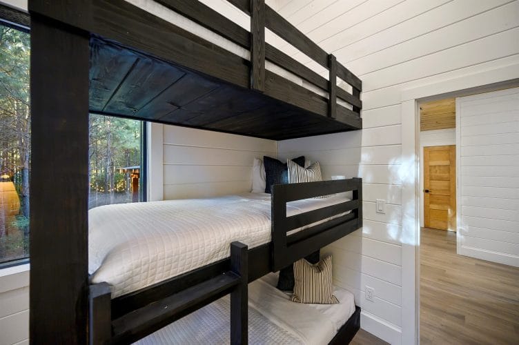 Black bunk with white bedding beside a window