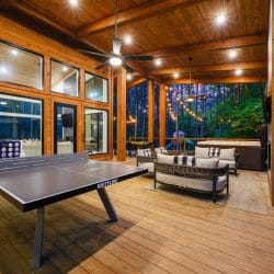 Covered deck with a ping pong table and lounge seating under a wood ceiling