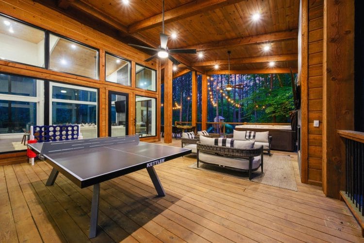 Covered deck with a ping pong table and lounge seating under a wood ceiling