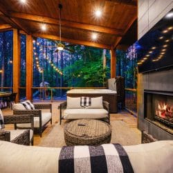 Covered patio with a tile fireplace burning, a big TV and wicker lounge seating
