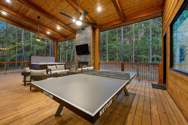 Ping pong table on the covered deck with the hot tub and seating beyond