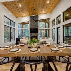 Long wood dining table set for a meal, with the fireplace and living area behind