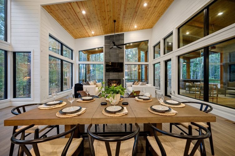 Long wood dining table set for a meal, with the fireplace and living area behind
