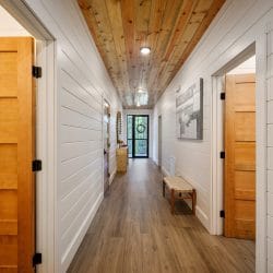 Hallway with wood doors and a plank ceiling leading to a glass front door