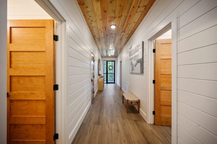 Hallway with wood doors and a plank ceiling leading to a glass front door