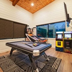 Game room with a pool table, arcade cabinets and a basketball game under a plank ceiling