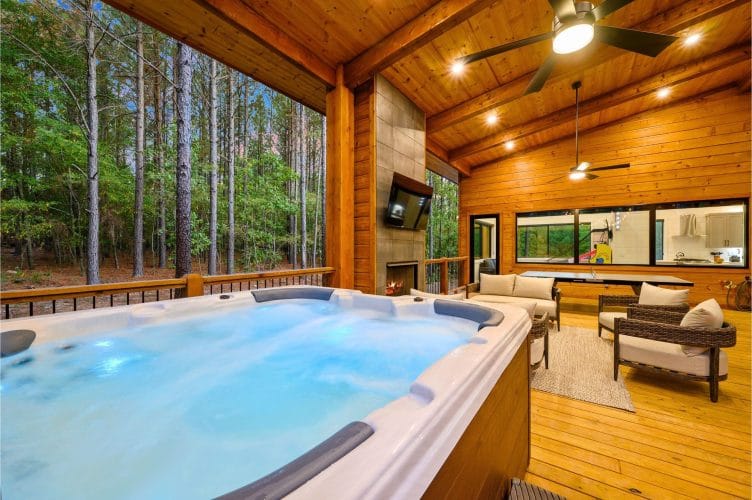 Hot tub on the covered deck with a ceiling fan overhead and seating beyond