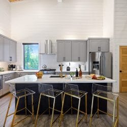 Kitchen with gray cabinets and a white island with four clear stools
