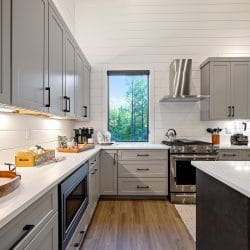 Kitchen counters and range with gray cabinets and a window