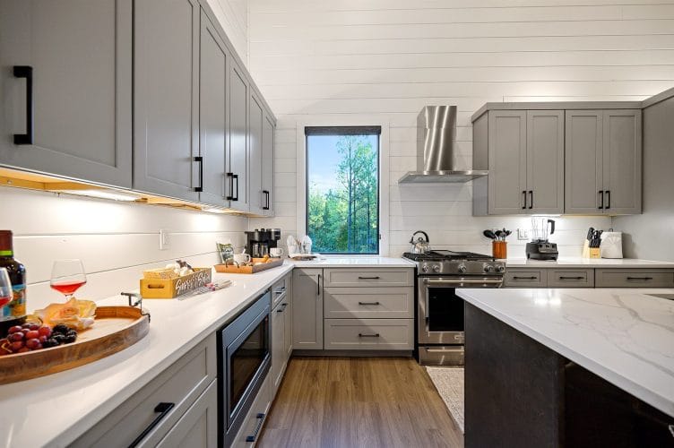 Kitchen counters and range with gray cabinets and a window