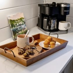 Keurig coffee maker with a tray of muffins and croissants on a white counter