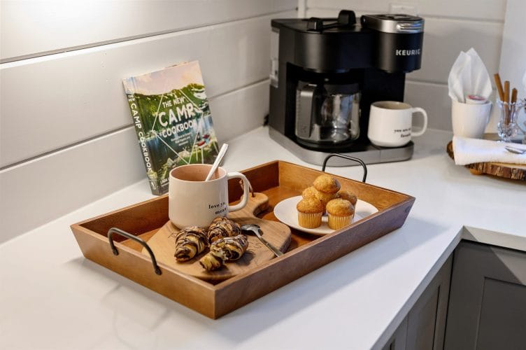 Keurig coffee maker with a tray of muffins and croissants on a white counter