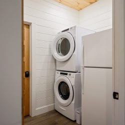 Stacked washer and dryer beside a refrigerator in a laundry closet
