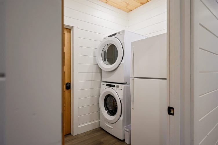 Stacked washer and dryer beside a refrigerator in a laundry closet