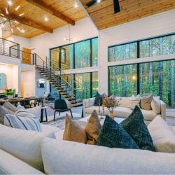 Great room with a two-story ceiling, an open staircase, a wall of windows and a long white sofa