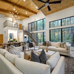 Great room with sofas, a TV and the stair railing under a tall plank ceiling