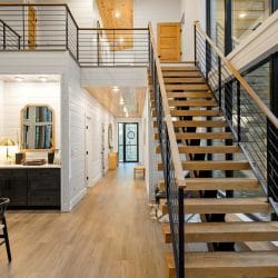 Open wooden stairs with a cable railing and a hallway beyond