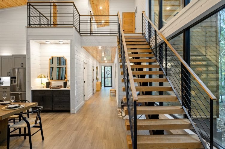 Open wooden stairs with a cable railing and a hallway beyond