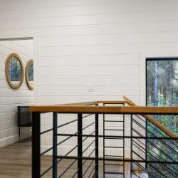 Upstairs landing with a stair railing and a tall window