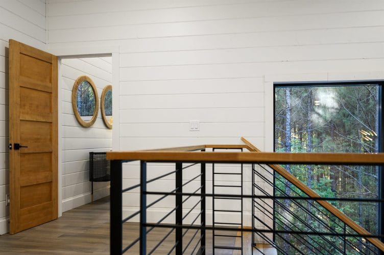 Upstairs landing with a stair railing and a tall window