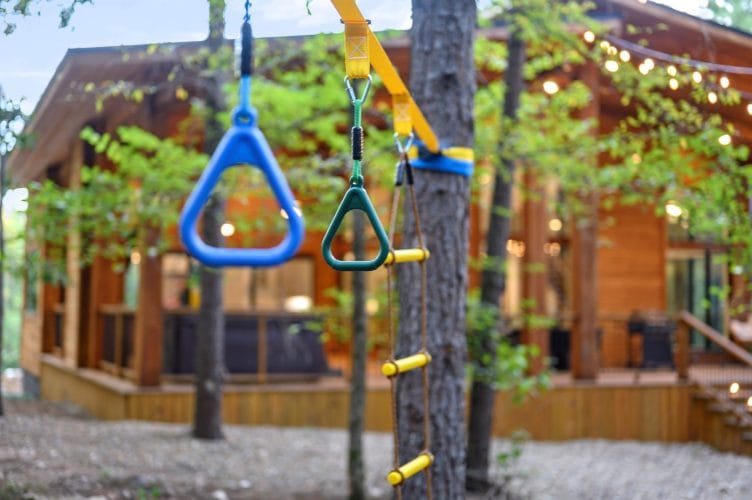 Ring swing hanging from a tree with the cabin glowing behind