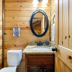 Half bath with a round mirror and a granite vanity