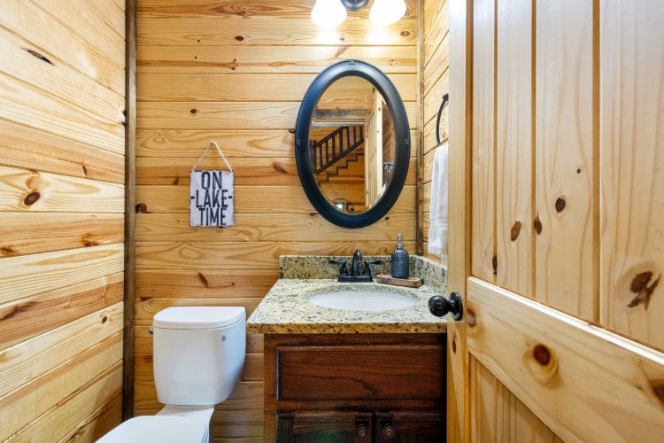 Half bath with a round mirror and a granite vanity