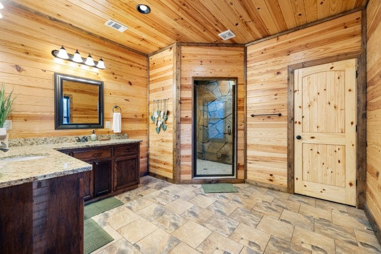 Bathroom with a granite vanity and a glass-door stone shower