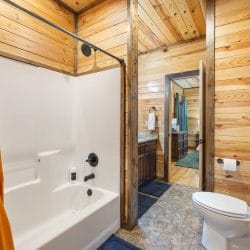 Tub-shower with an orange curtain and a vanity beyond